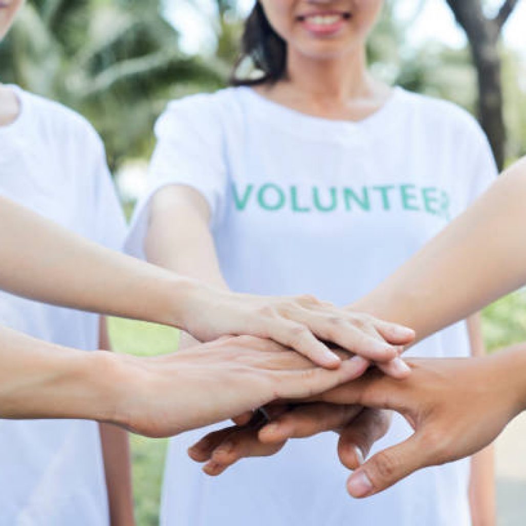 Close-up image of volunteers stacking hands to express support and unity before starting work